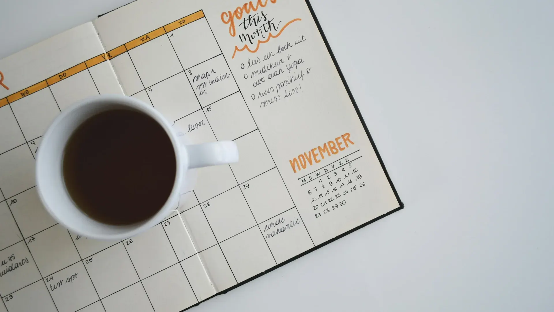 Un agenda mensuel ouvert avec une tasse de café posée dessus